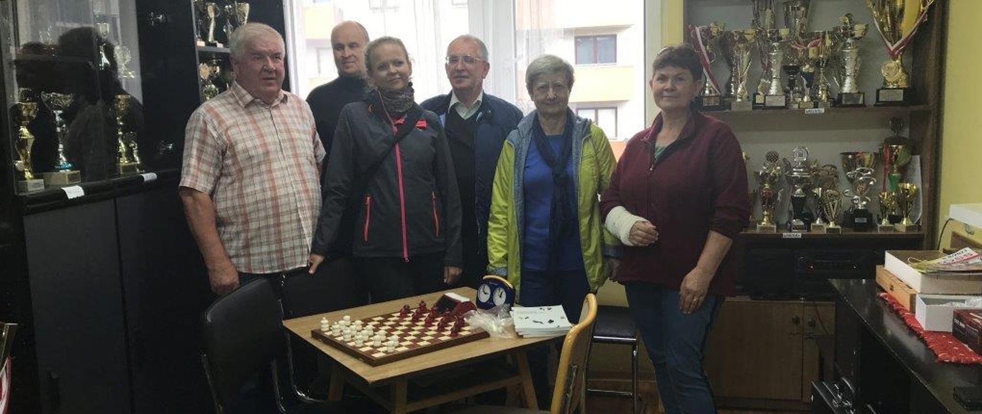 Członkowie Koła pozują przy stole z rozłożonymi warcabami