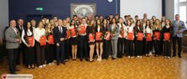 Szeroki kadr dokumentujący całą społeczność stypendystów oraz zaproszonych gości w auli liceum.