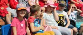 Dzieci siedzą na trybunach w roli widzów