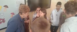 Autorka książek pani Celina Cempa pochyla się w rozmowie do uczennicy, wokół stoją inni uczniowie