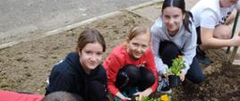 Dzieci sadzą kwiaty przed szkołą