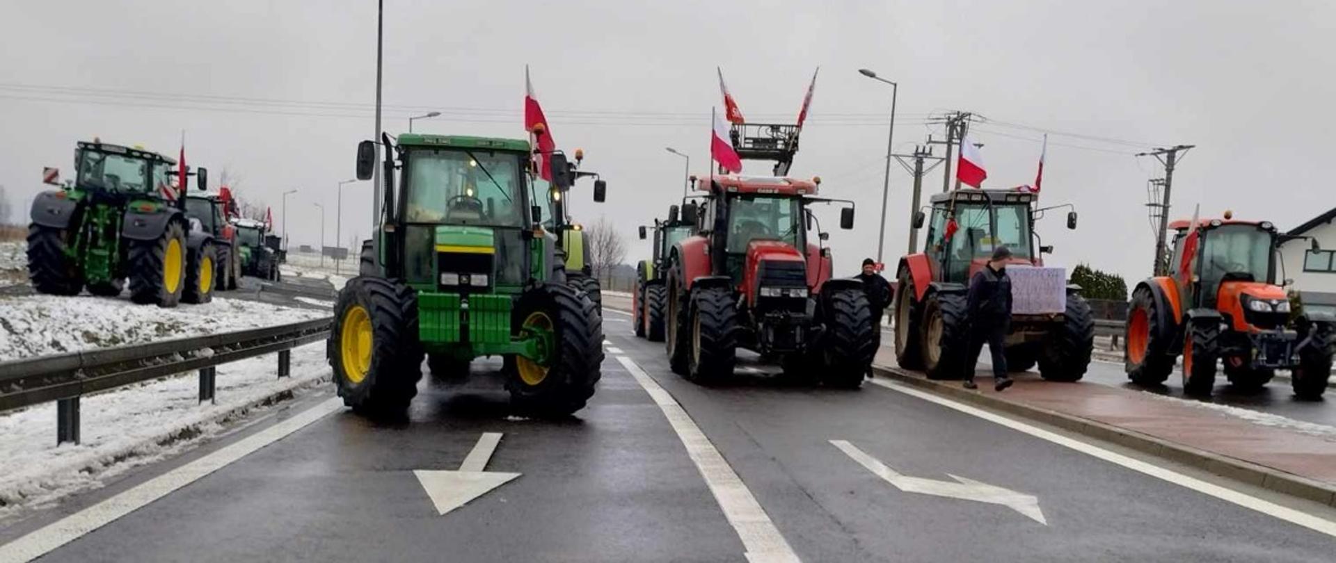 Na fotografii stojące na drodze traktory blokujące drogę. 