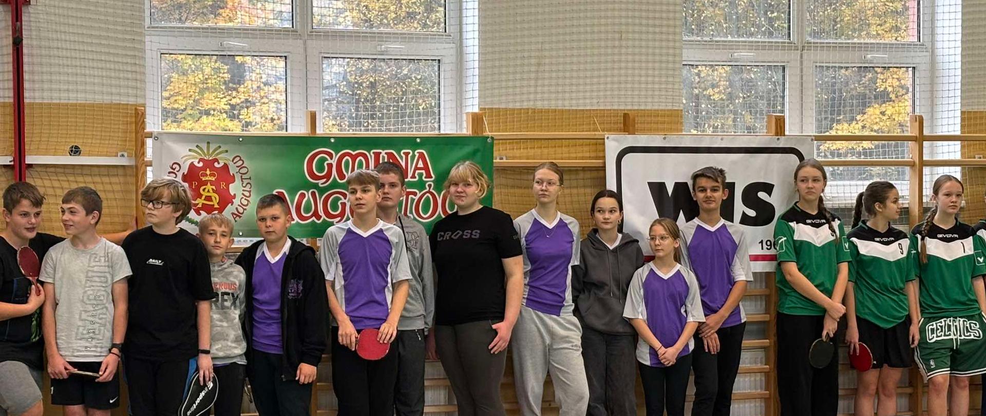 Sala gimnastyczna. Grupa uczniów ubranych w sportowe stroje.