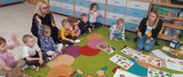 Uczymy się zasad zdrowego odżywiania - przed dziećmi leżą tablice z warzywami i owocami, dzieci biorą aktywny udział w lekcji z udziałem nauczycielki Justyny Moroz i Pani Dyrektor Doroty Eweliny Durzyńskiej.