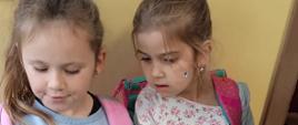 Dwie uczennice z klasy 1 czytają książkę na przerwie podczas akcji bibliotecznej "Przerwa na czytanie"