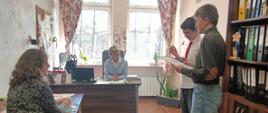 Dwóch chłopców przedstawicieli Samorządu Uczniowskiego częstuje składa życzenia pani dyrektor w gabinecie dyrektorskim i siedzącej tam pani pedagog