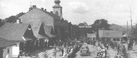Archiwalna fotografia przedstawia widok na rynek, urząd gminy i kościół podczas przejazdu prezydenta Ignacego Mościckiego 