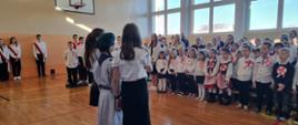 Społeczność szkolna ogląda występ uczniów z okazji Narodowego Święta Niepodległości w sali gimnastycznej