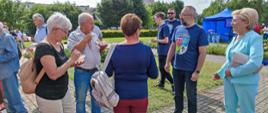 Festyn Profilaktyczno Zdrowotny w ogrodach przasnyskiego szpitala. Zdjęcie przedstawia uczestników Festynu kosztujących zdrowe warzywne sałatki podczas rozmowy ze Starostą Powiatu Przasnyskiego Krzysztofem Bieńkowskim oraz Poseł Anną Cicholską.