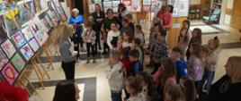 Na zdjęciach widać uczestników wernisażu - dzieci stoją przed prowadzącymi uroczystość, wokół nich prezentacja prac