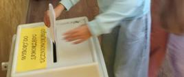 Uczennica wrzuca swój głos do urny, inne dzieci czekają w kolejce