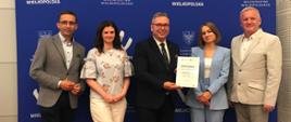 Przedstawiciele Gminy Budzyń na wspólnym zdjęciu, pięć osób w rzędzie, jedna w środku prezentuje certyfikat