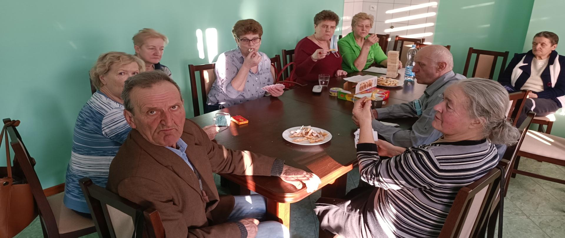 Seniorzy przy stole spożywający wypieki