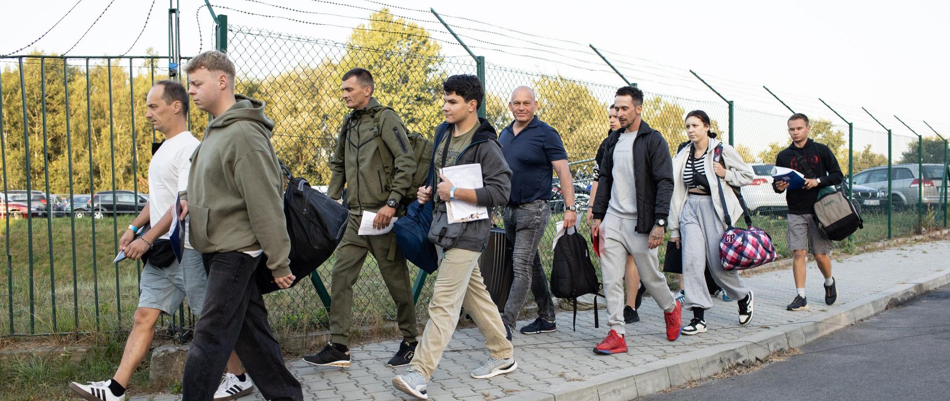 Zdjęcie przedstawia kobiety i mężczyzn w średnim wieku maszerujących chodnikiem