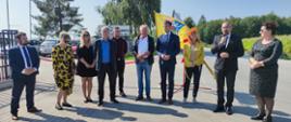 Powiat Przasnyski zrealizował remont odcinka drogi powiatowej na trasie Kijewice-Mchowo. Fotografia przedstawia przemawiającego Starostę Przasnyskiego. Od lewej stoją: Etatowy Członek Zarządu Powiatu Przasnyskiego Paweł Mostowy, dwie pracownice Powiatowego Zarządu Dróg w Przasnyszu, Dyrektor Powiatowego Zarządu Dróg w Przasnyszu Kazimierz Pióro, pracownik Powiatowego Zarządu Dróg w Przasnyszu, właściciel firmy znajdującej się przy wyremontowanym odcinku Grzegorz Borkowski, Kierownik Delegatury Mazowieckiego Urzędu Wojewódzkiego w Ostrołęce Marcin Grabowski, Wójt Gminy Przasnysz Grażyna Wróblewska, Starosta Powiatu Przasnyskiego Krzysztof Bieńkowski, Członek Zarządu Powiatu Przasnyskiego Renata Wenda.