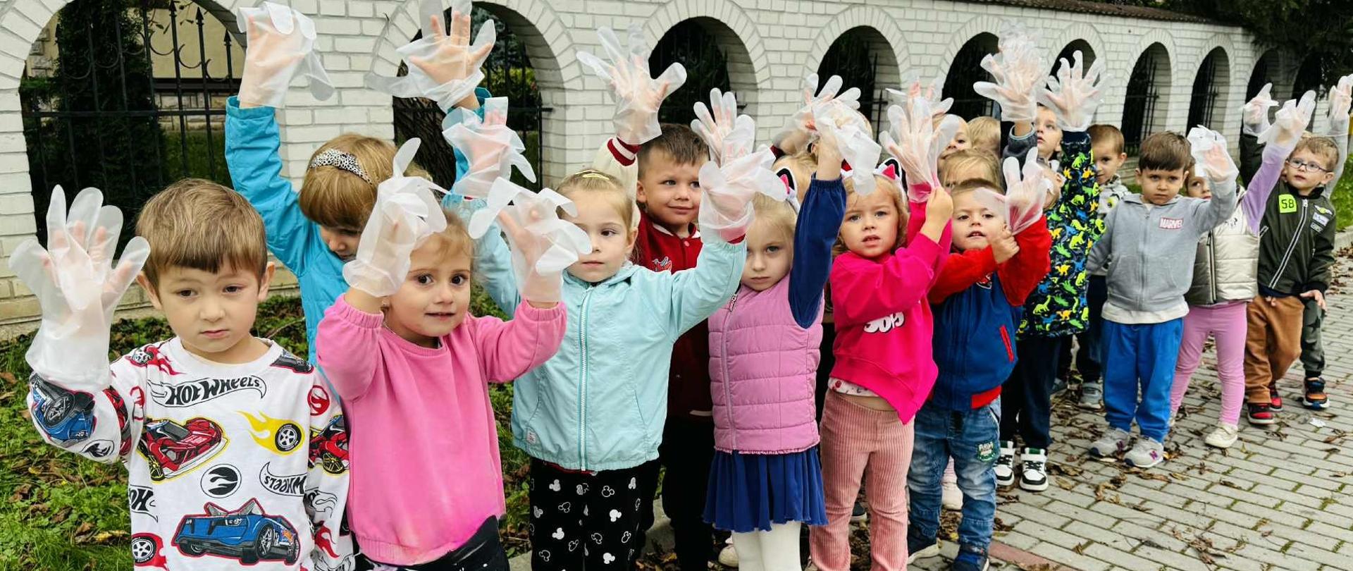 Grupa czterolatków zbiera śmieci na terenach wokół przedszkola w ramach akcji "Sprzątanie Świata"