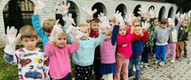 Grupa czterolatków zbiera śmieci na terenach wokół przedszkola w ramach akcji "Sprzątanie Świata"