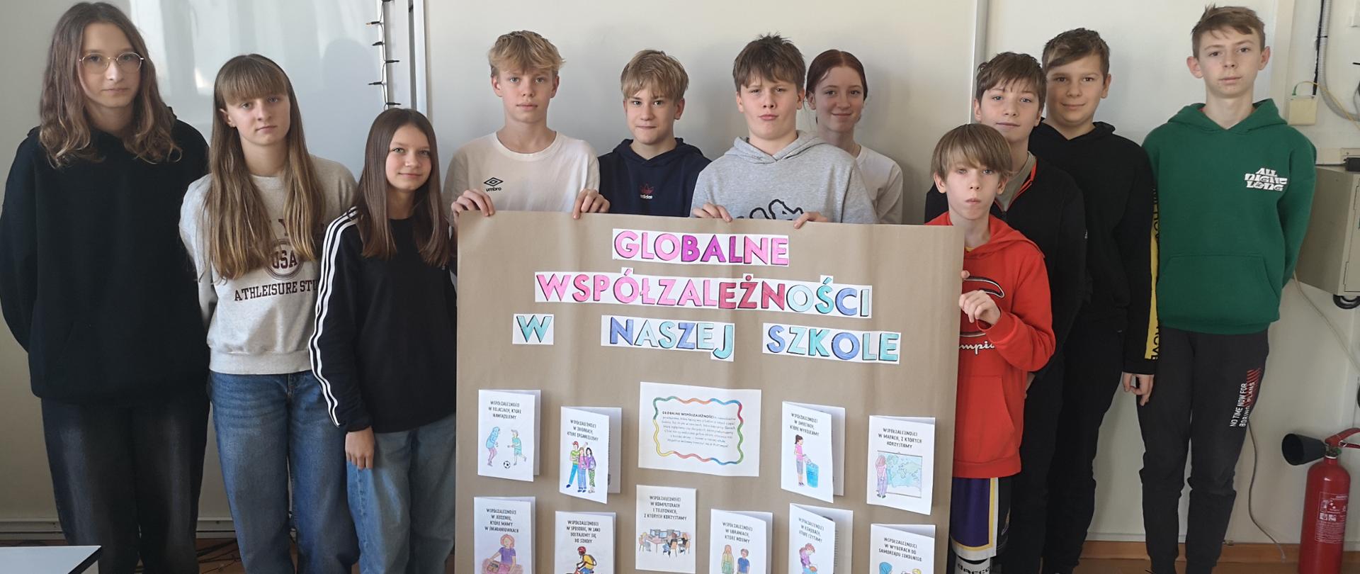 Uczniowie klasy 7 prezentują plakat pt. Globalne współzależności w naszej szkole