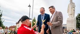 Wiceprezes Klubu Sportowego - Lotnik Ostrów wręcza symboliczne statuetki Staroście Powiatu Proszowickiego oraz Burmistrzowi Gminy i Miasta Proszowice jako wspólorganizatorom III Proszowickiego Thriatlonu Lotników