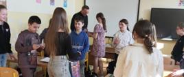 Dziewczynki weszły do klasy na lekcję religii i częstują cukierkami chłopców i księdza