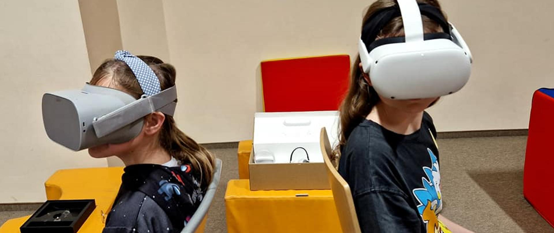 Dziewczynki w specjalnych okularach oglądają wirtualną rzeczywistość. 