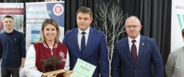 Przedstawicielka Politechniki Białostockiej odbiera nagrodę Starosty Hajnowskiego - obok niej do zdjęcia pozują Starosta Hajnowski i Zastępca Burmistrza Miasta Hajnówka