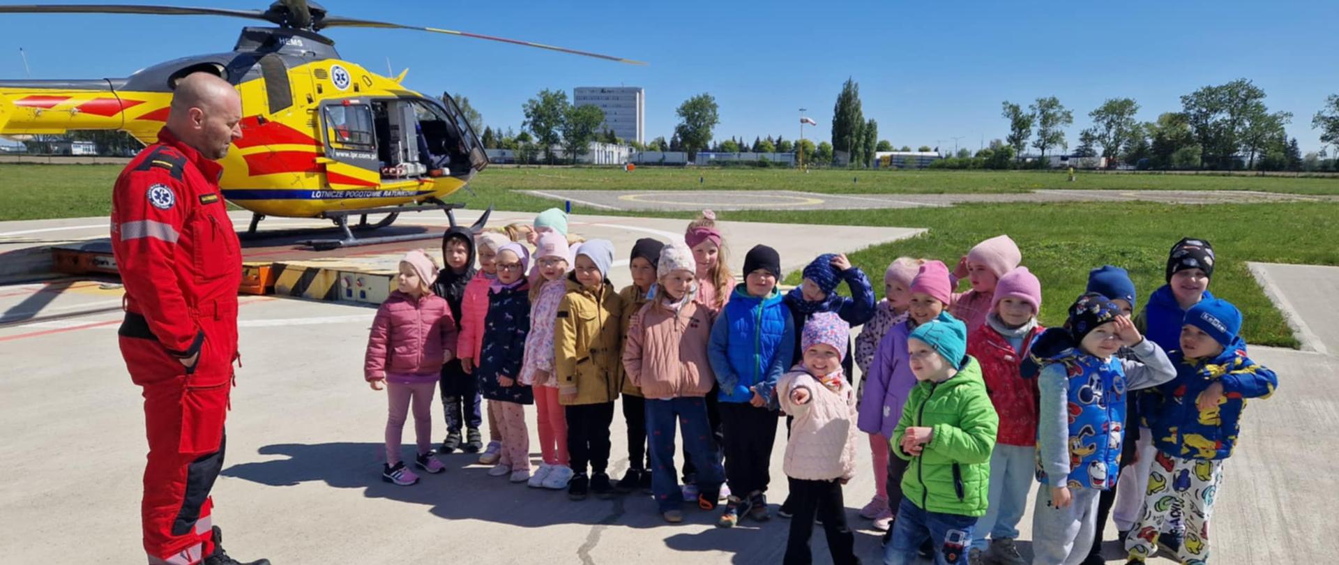 Grupa dzieci obok ratownika na tle helikoptera medycznego