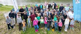 Grupa dzieci pozuje do zdjęcia na grobli stawu