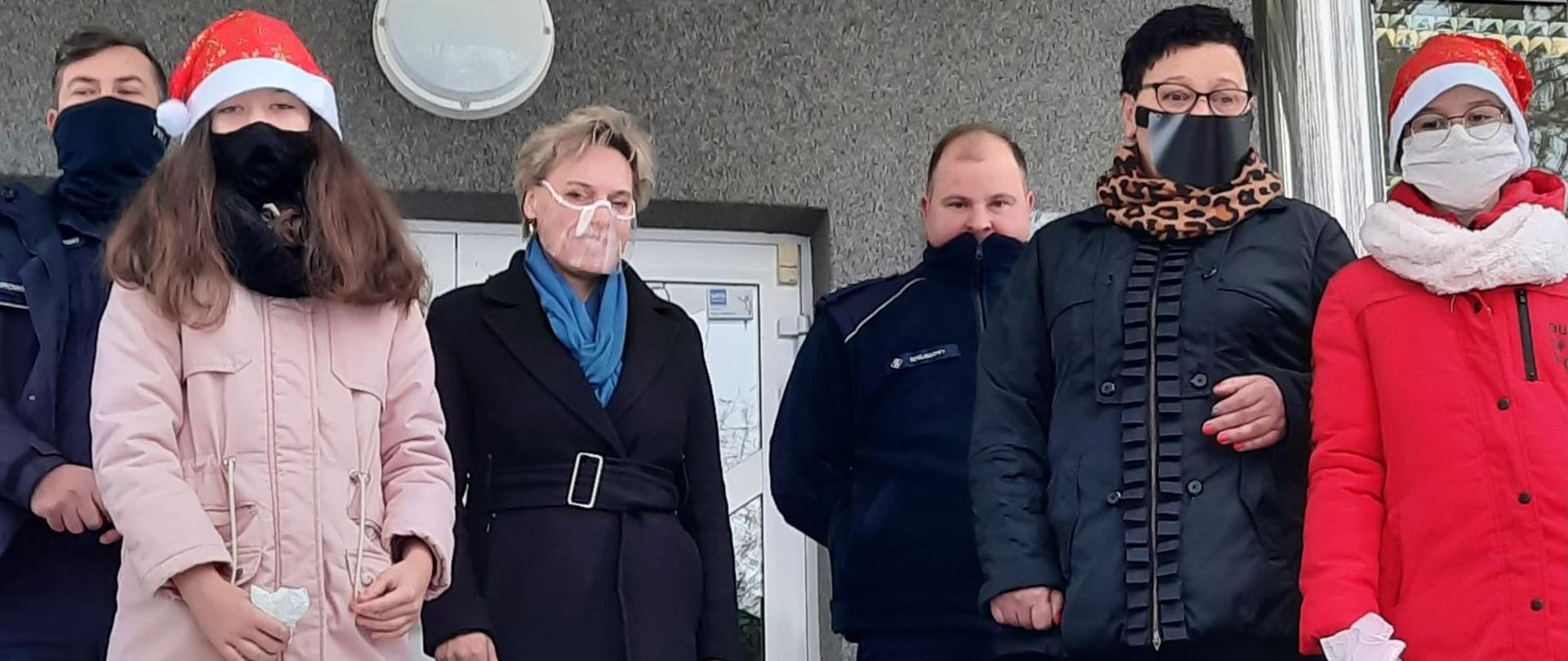 Wójt Apolonia Stasiuk z uczennicami Julką Olszewską i Amelką Borychowską, kierownik GOPS Teresą Stasiuk oraz Panami policjantami przed budynkiem gminy