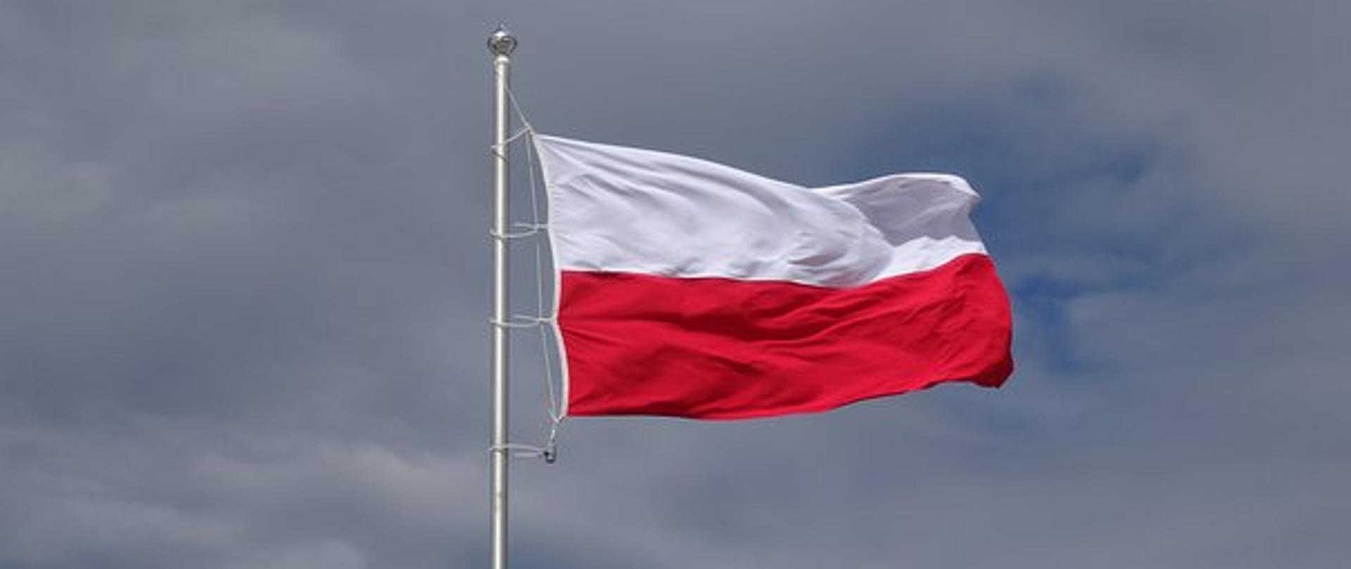 flaga polski w barwach białej u góry i czerwonej na dole zamocowana na maszcie