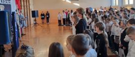 Społeczność szkolna ogląda występ uczniów z okazji Narodowego Święta Niepodległości w sali gimnastycznej