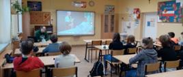 Dzieci siedzą w klasie i oglądają prezentację