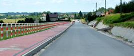 remontowany odcinek drogi, po prawej stronie robione zjazdy do posesji po lewej czerwony chodnik z barierkami 