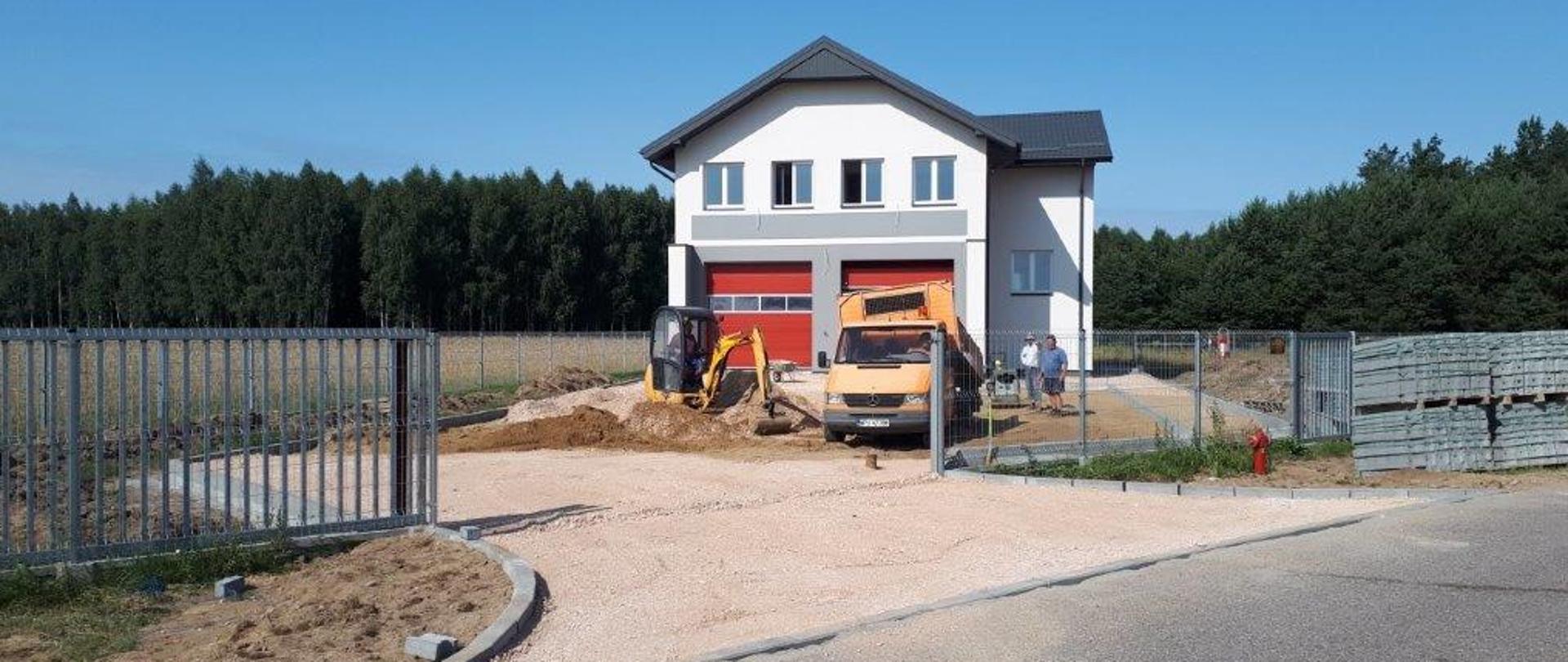Wykonanie podjazdu i parkingu przed budynkiem remizy OSP Stara Wieś. Na zdjęciu mała koparka, samochód wywrotka i pracujący mężczyźni. W tle budynek remizy.