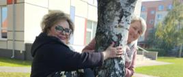Dzieci i nauczycielki przytulają się do drzewa