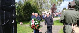 Przewodniczący Rady Miejskiej, Burmistrz Miasta i Gminy Budzyń oraz jego Zastępca składający wiązankę kwiatów pod Pomnikiem Pamięci Narodowej.
