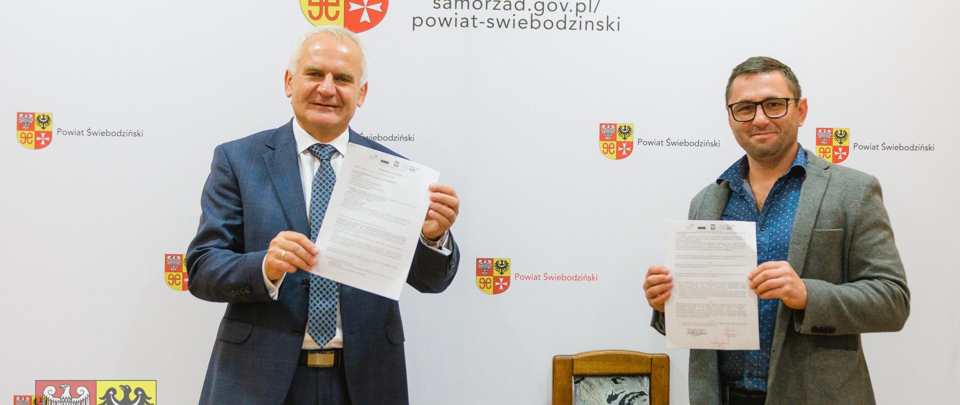 dwóch mężczyzn pokazujących podpisane dokumenty