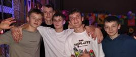 Pięciu uczniów z klasy 8 pozuje do zdjęcia trzymając się rękami za ramiona