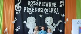 Zdjęcie dzieci na podeście w tle czarna tablica z napisem rozśpiewane przedszkolaki