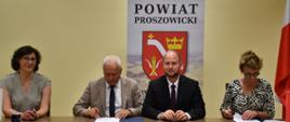 Przy biurku przedstawiciele Zarządu Powiatu Proszowickiego i Gminy Koniusza podpisują umowę na "Wyrównywanie różnic między regionami III”