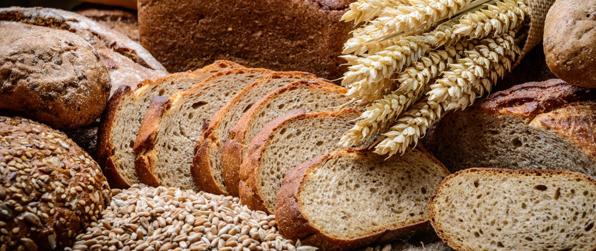 Zdjęcie przedstawiające pokrojony chleb, oraz kłosy zboża
